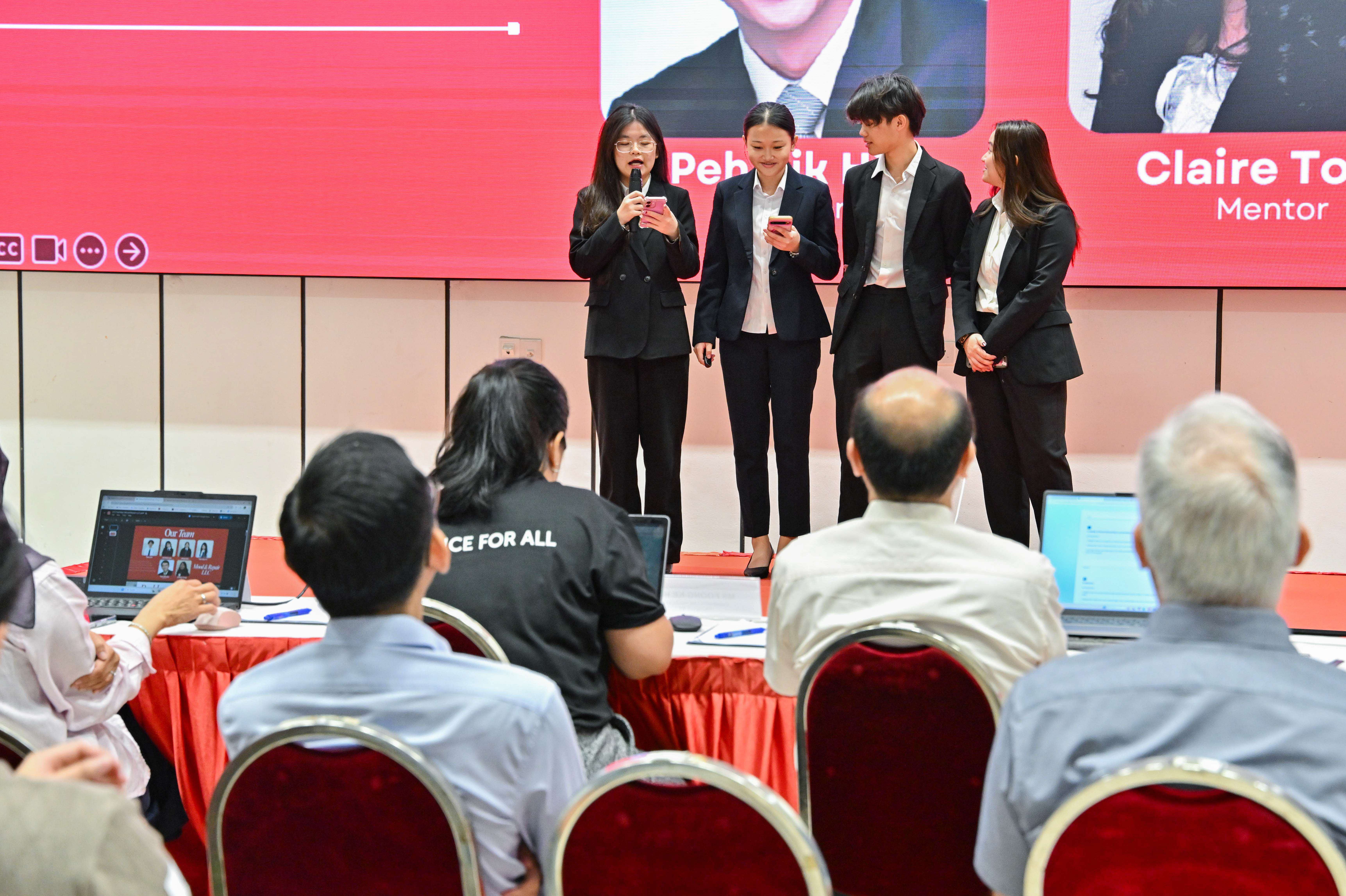 Four students presenting in front of the panel of judges